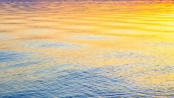 Klar vattenstruktur i blått och orange. Bakgrund av havet och havet bakgrundsbelyst av solen. Mjuka vågor. Naturligt vatten — Stockfoto