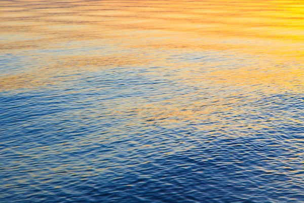 Struttura chiara dell'acqua in blu e arancione. Sullo sfondo dell'oceano e del mare retroilluminato dal sole. Onde morbide. Acqua naturale — Foto Stock