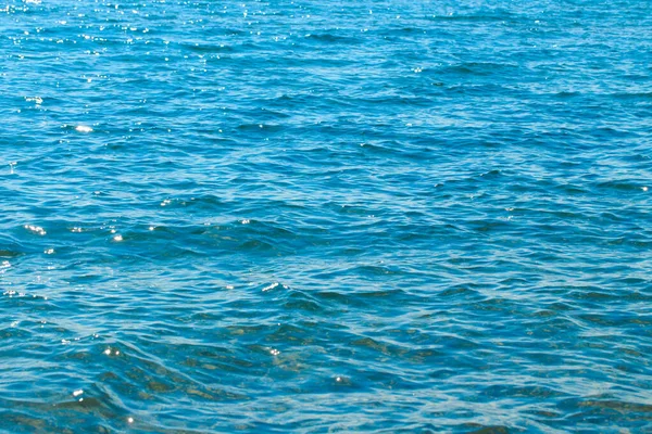 Struttura chiara dell'acqua in blu e arancione. Sullo sfondo dell'oceano e del mare retroilluminato dal sole. Onde morbide. Acqua naturale — Foto Stock