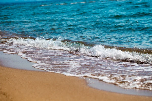 Písčitá pláž a modrá mořská vlna. Krásný přirozený podklad. Turistika a cestování. Stock Snímky