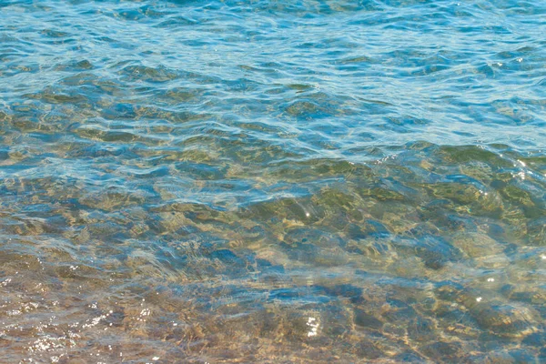 Textura clara da água em azul e laranja. Fundo do oceano e do mar iluminado pelo sol. Ondas suaves. Água natural — Fotografia de Stock