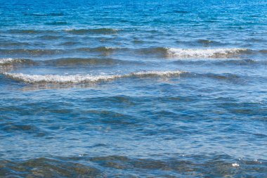 Mavi ve turuncu berrak su dokusu. Okyanusun arka planı ve güneş tarafından aydınlatılan deniz. Yumuşak dalgalar. Doğal su.