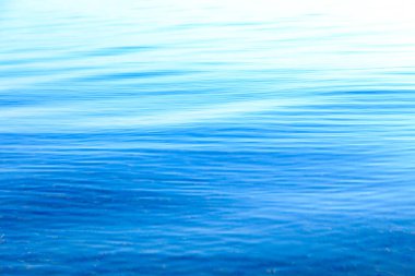 Mavi ve turuncu berrak su dokusu. Okyanusun arka planı ve güneş tarafından aydınlatılan deniz. Yumuşak dalgalar. Doğal su.