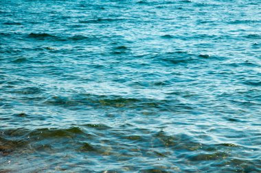 Mavi ve turuncu berrak su dokusu. Okyanusun arka planı ve güneş tarafından aydınlatılan deniz. Yumuşak dalgalar. Doğal su.