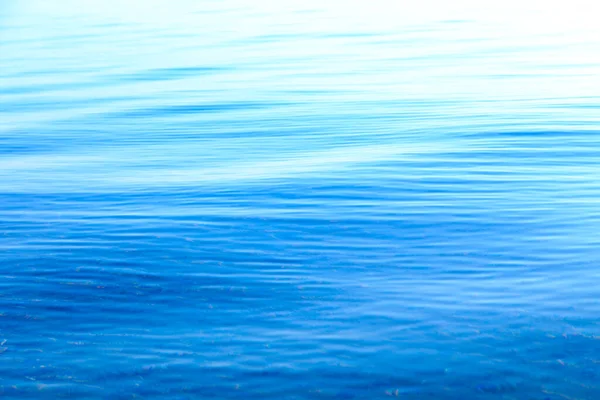 Klare Wasserstruktur in Blau und Orange. Hintergrund des Ozeans und des Meeres im Gegenlicht der Sonne. Weiche Wellen. natürliches Wasser — Stockfoto