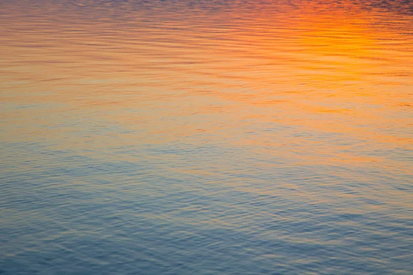 Clear water texture in blue and orange. Background of the ocean and the sea backlit by the sun. Soft waves. Natural water — Stock Photo, Image