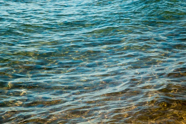 Heldere watertextuur in blauw en oranje. Achtergrond van de oceaan en de zee verlicht door de zon. Zachte golven. Natuurlijk water — Stockfoto