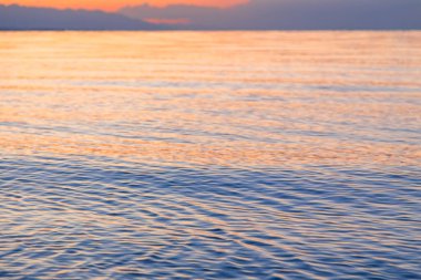 Mavi ve turuncu berrak su dokusu. Okyanusun ve denizin arkaplanı güneşle aydınlanıyor..