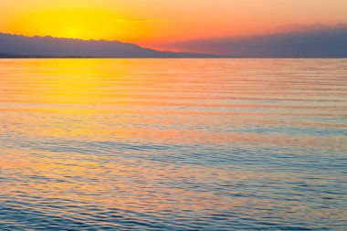 Mavi ve turuncu berrak su dokusu. Okyanusun ve denizin arkaplanı güneşle aydınlanıyor..