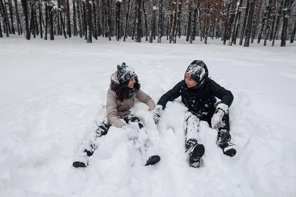 A girl and a guy lay on a snow