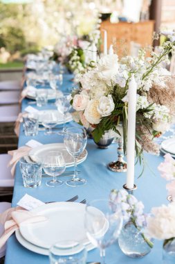 Çiçek ve mum mavi masa örtüsü üzerinde gümüş bir şamdan ile dekore edilmiş Festival tablo