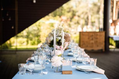 Çiçekler ve mumlarla süslenmiş mavi masa örtüsü ile uzun Festival tablo