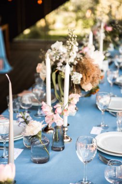 Çiçekler ve mumlarla süslenmiş mavi masa örtüsü ile uzun Festival tablo