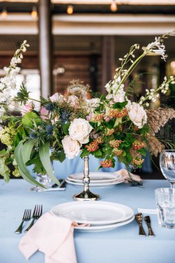 Çiçek ve mum mavi masa örtüsü üzerinde gümüş bir şamdan ile dekore edilmiş Festival tablo