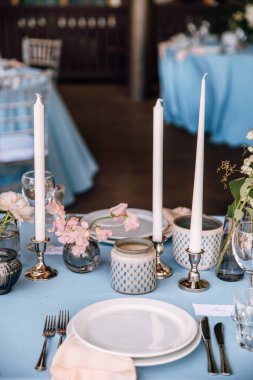 Çiçek ve mum mavi masa örtüsü üzerinde gümüş bir şamdan ile dekore edilmiş Festival tablo