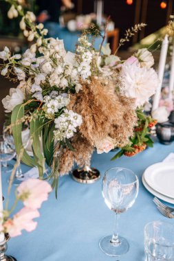 Çiçek ve mum mavi masa örtüsü üzerinde gümüş bir şamdan ile dekore edilmiş Festival tablo