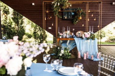 İki şenlikli masa altında garland rustik tarzda yeşillikleri ile Milano masa örtüsü ve beyaz çiçeklerle dekore edilmiş