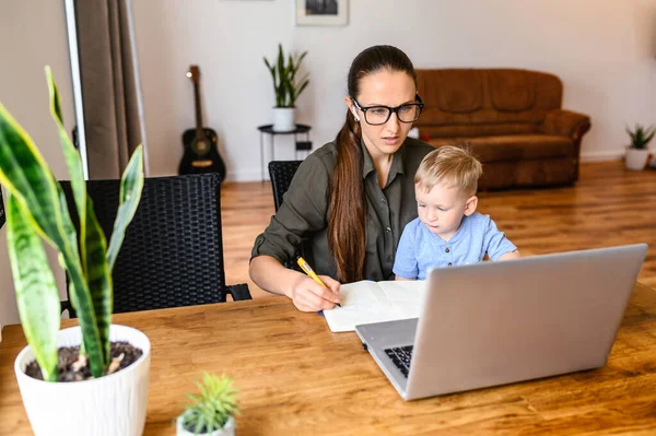 Mamá trabaja en casa con un niño pequeño en sus brazos — Foto de Stock