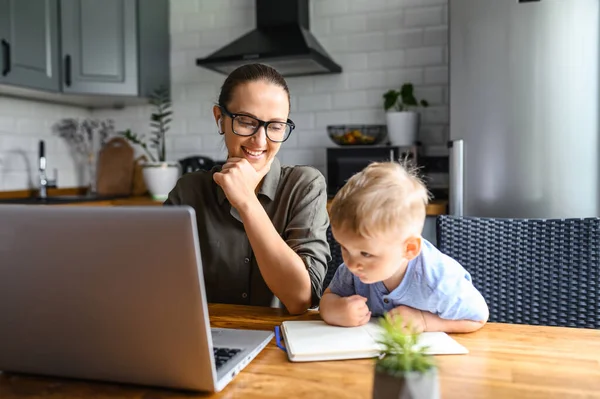 Jovem mãe trabalha de casa com laptop — Fotografia de Stock