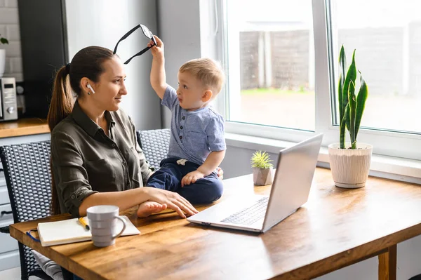 Jonge moeder werkt vanuit huis met laptop — Stockfoto