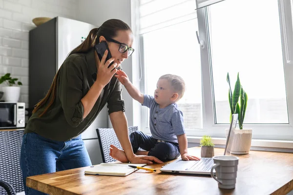 Mamá trabaja en casa, niño pequeño cerca — Foto de Stock