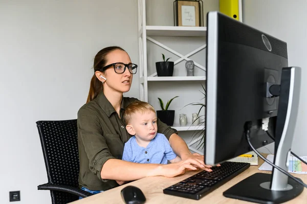 Mother works in home office with kid on laps