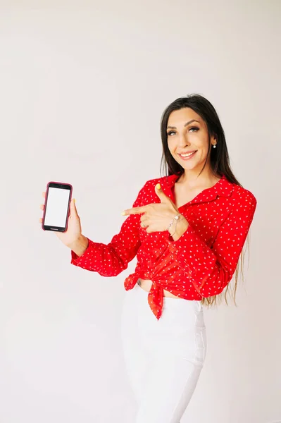 Mujer joven señalando un teléfono en su mano — Foto de Stock