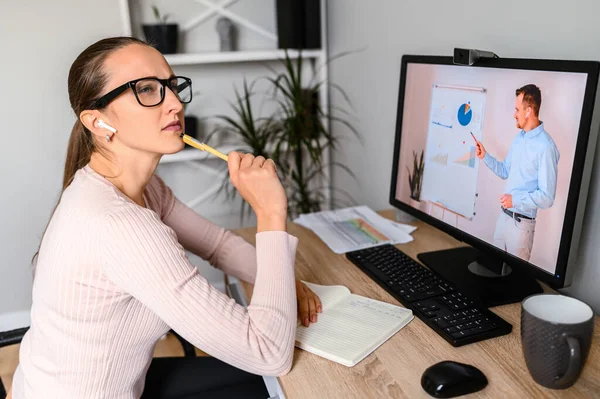 Uma mulher no escritório está assistindo aulas online — Fotografia de Stock