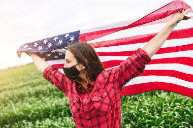 Amerikan bayrağı taşıyan maskeli bir kız.