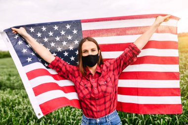 Amerikan bayrağı taşıyan maskeli bir kız.