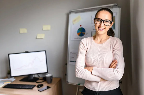 Souriante fille dans les lunettes regarde à la caméra dans le bureau — Photo