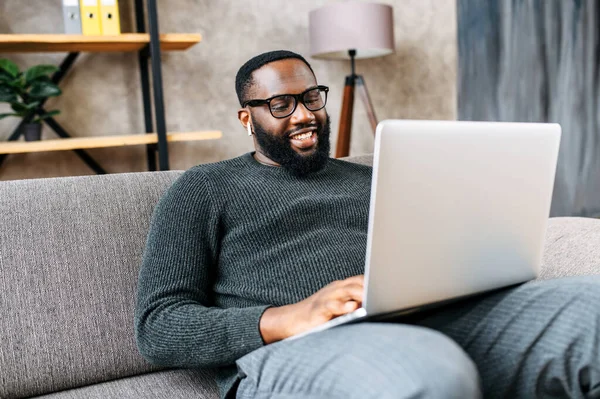 Afroameričan sedí na pohovce s laptopem — Stock fotografie