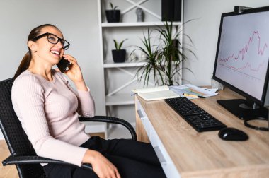 Kadın evde çalışırken telefonla konuşuyor.