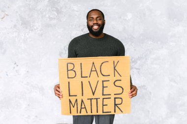 Afro-Amerikalı adam tabelayla duruyor.