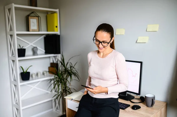 Donna guarda lo schermo del telefono in home office — Foto Stock