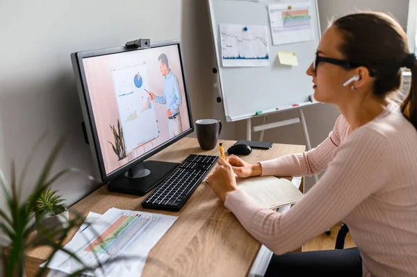 En kvinna på kontoret tittar på online lektioner — Stockfoto