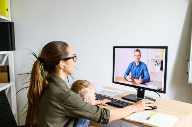 Annesi evde kucağında çocukla çalışıyor.