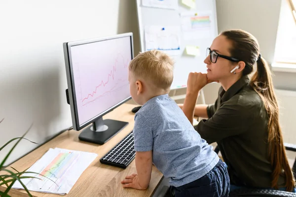Mother works in home office, toddler near