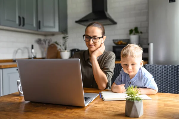 Young mother works from home with laptop