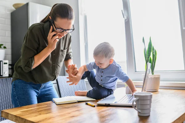 Mamá trabaja en casa, niño pequeño cerca — Foto de Stock