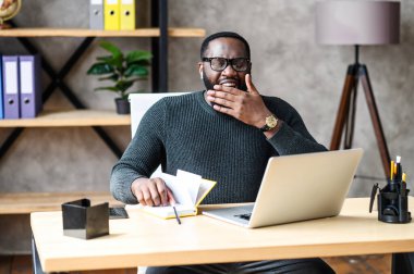 Ofiste dizüstü bilgisayar kullanan Afro-Amerikalı bir adam.