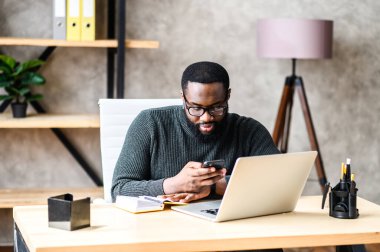 Ofiste dizüstü bilgisayar kullanan Afro-Amerikalı bir adam.