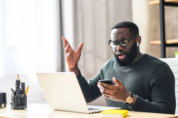 Um afro-americano usando laptop no escritório — Fotografia de Stock