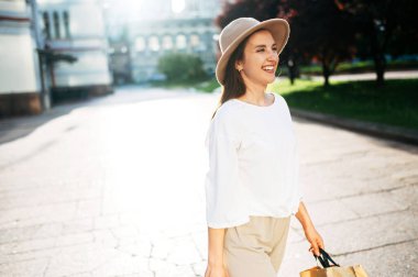 Şehir merkezinde şapkalı hoş bir kadın yürüyor.