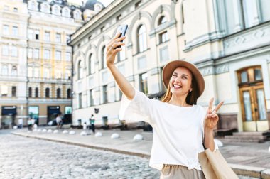 Şapkalı neşeli genç kadın selfie çekiyor.