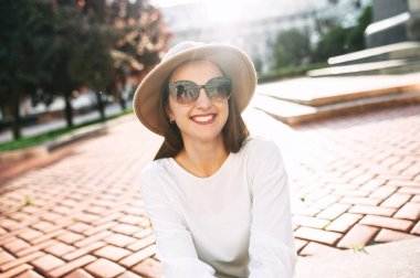 Şehir merkezinde şapkalı hoş bir kadın yürüyor.