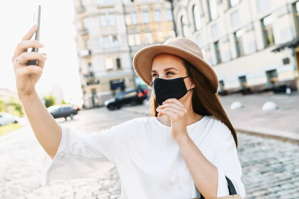 Jovem mulher em máscara médica está tomando selfie — Fotografia de Stock