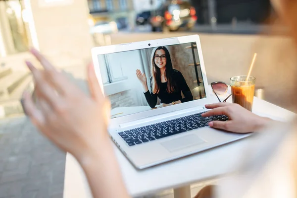 女の子は屋外カフェでビデオ通話のためのラップトップを使用しています — ストック写真