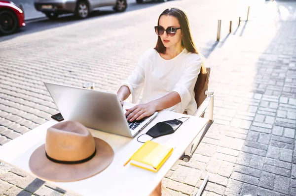 Жінка сидить з ноутбуком в літньому кафе — стокове фото