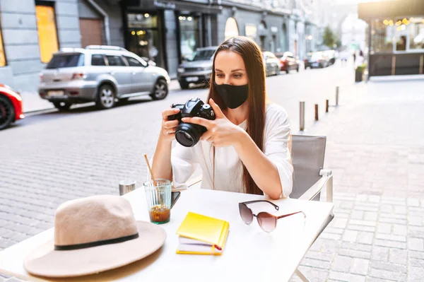 Donna in maschera medica con una macchina fotografica nel caffè — Foto Stock